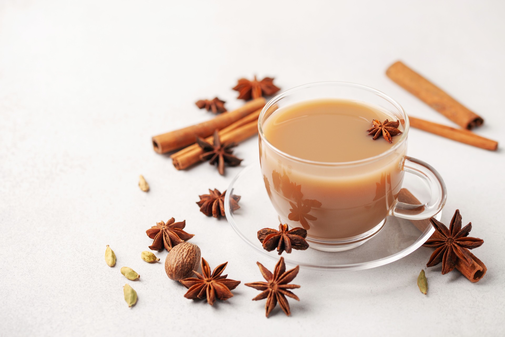 Masala tea or karak chai in a glass cup with cardamom, star anise and cinnamon.