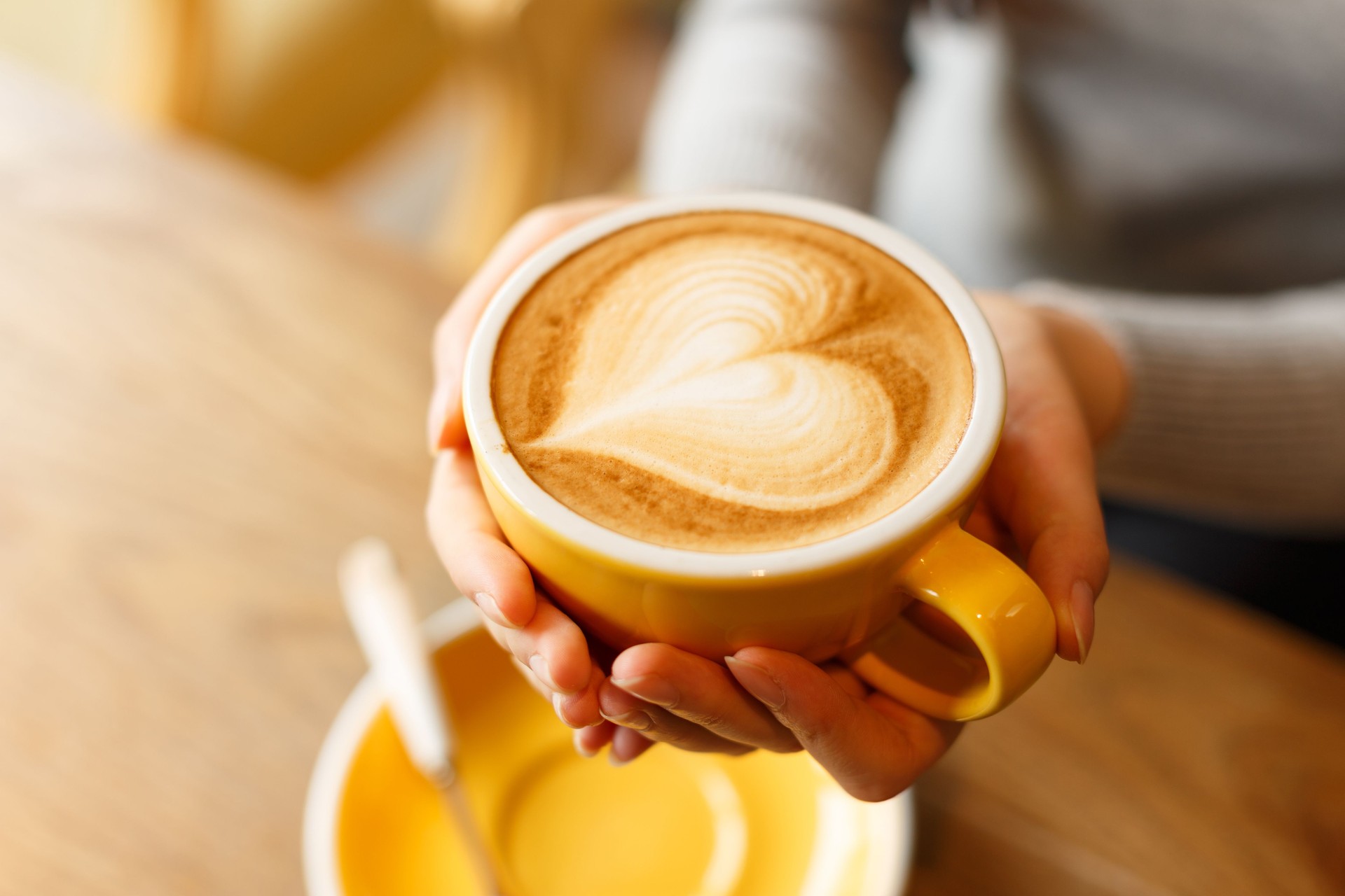 lady's hands holding cup with sth heart-shaped